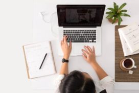 Overhead image of person with an open laptop and a pen and paper avoiding job search procrastination