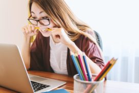 Woman sitting in front of her laptop nervously biting a pencil, interviewing weaknesses