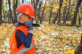 a little kid in a construction uniform and carrying a wrench