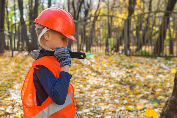 a little kid in a construction uniform and carrying a wrench