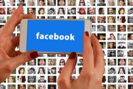 hands holding a smartphone with the facebook logo over a background grid of peoples' faces on screens