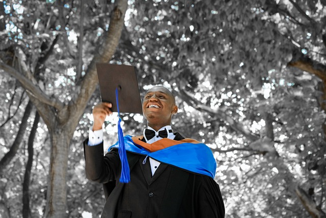 a young Black man in a suit and graduation robe throwing his mortarboard into the air