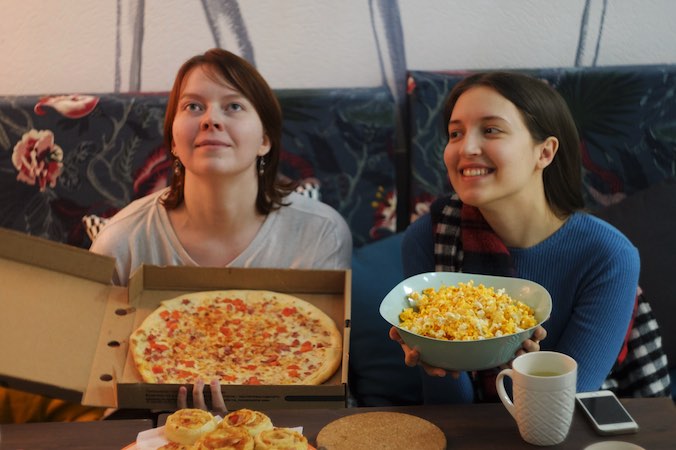 two people watching movies with pizza and popcorn