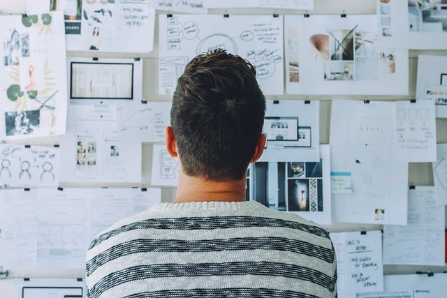 Brainstorming Business ideas: a person looks at a bulletin board with charts lists and inspiring images to think about business ideas