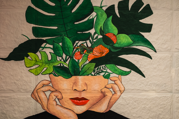 photograph of a painted mural of green plants growing out of a person's face, as if thoughts are literally growing